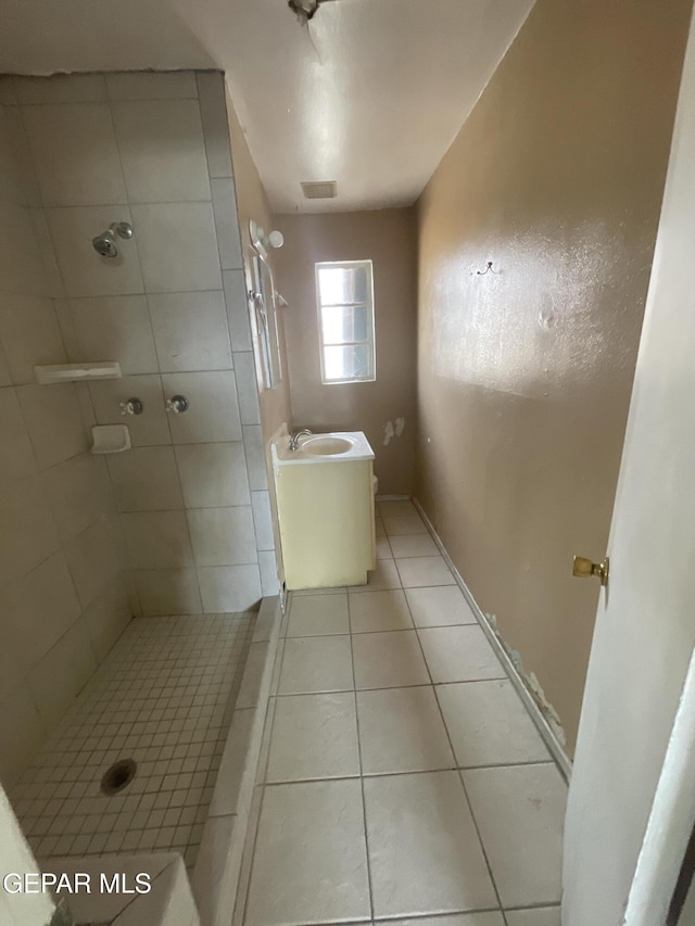 bathroom featuring tile patterned floors, vanity, and a tile shower