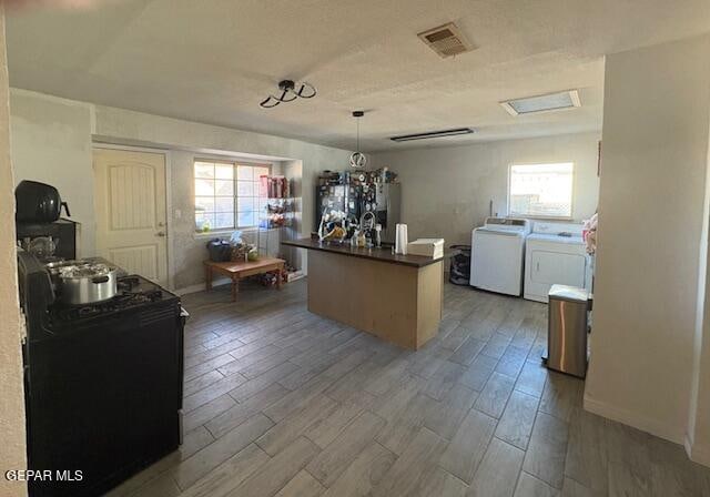 kitchen featuring an inviting chandelier, wood-type flooring, decorative light fixtures, and independent washer and dryer