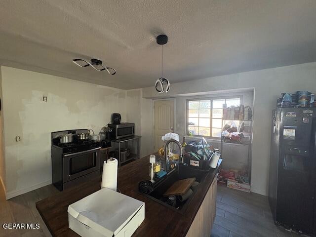 kitchen featuring a textured ceiling, stainless steel appliances, dark wood-type flooring, and sink