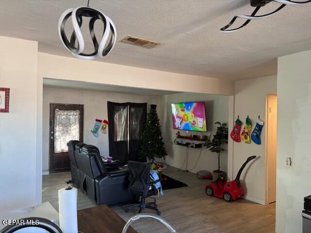 living room with a textured ceiling and light hardwood / wood-style flooring