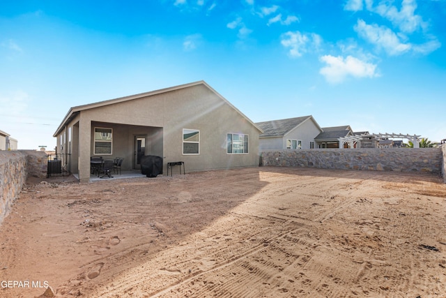 back of property with central AC unit and a patio