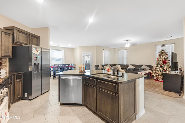 kitchen featuring a center island with sink, sink, ceiling fan, dark brown cabinetry, and stainless steel appliances