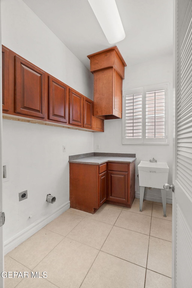 laundry area with cabinets, light tile patterned floors, hookup for a gas dryer, and electric dryer hookup