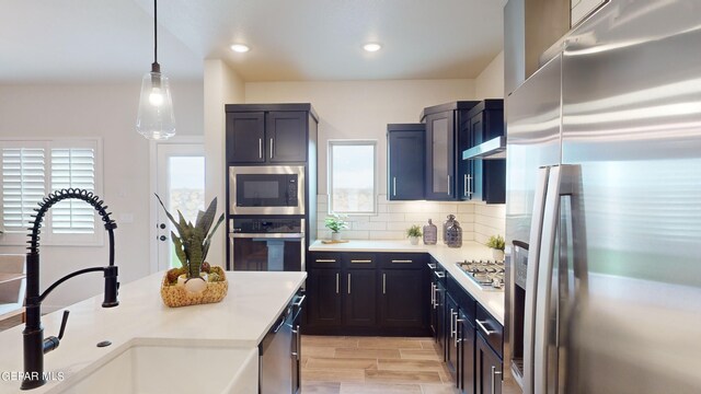 900 Stoke St, El Paso, TX 79928 - kitchen with appliances with stainless steel finishes, a sink, light countertops, decorative backsplash, and hanging light fixtures