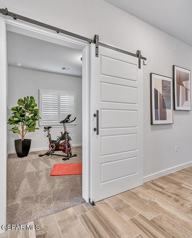 900 Stoke St, El Paso, TX 79928 - hallway with a barn door, light wood-type flooring, and baseboards