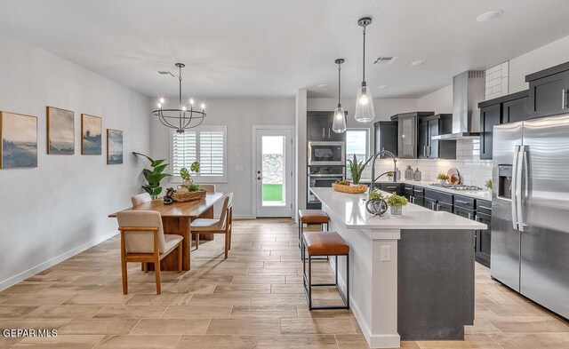 900 Stoke St, El Paso, TX 79928 - kitchen featuring stainless steel appliances, wall chimney exhaust hood, light countertops, backsplash, and dark cabinetry