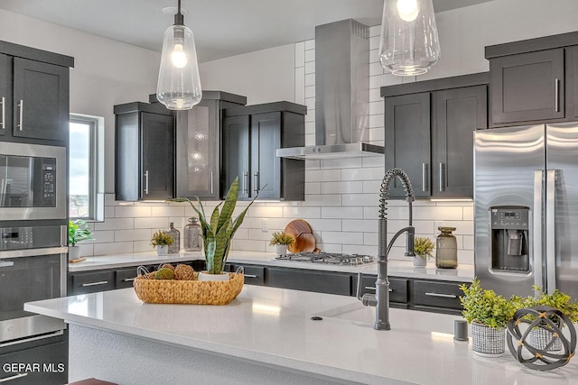 900 Stoke St, El Paso, TX 79928 - kitchen with wall chimney exhaust hood, appliances with stainless steel finishes, light countertops, decorative backsplash, and hanging light fixtures