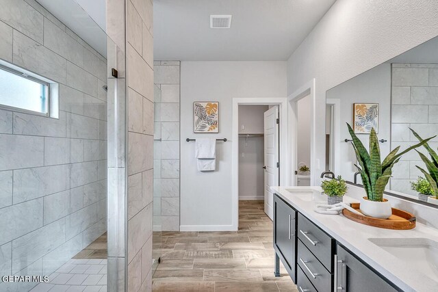 900 Stoke St, El Paso, TX 79928 - bathroom with double vanity, a walk in shower, baseboards, and wood finish floors