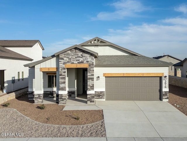 view of front of home with an attached garage, stone siding, concrete driveway, and roof with shingles