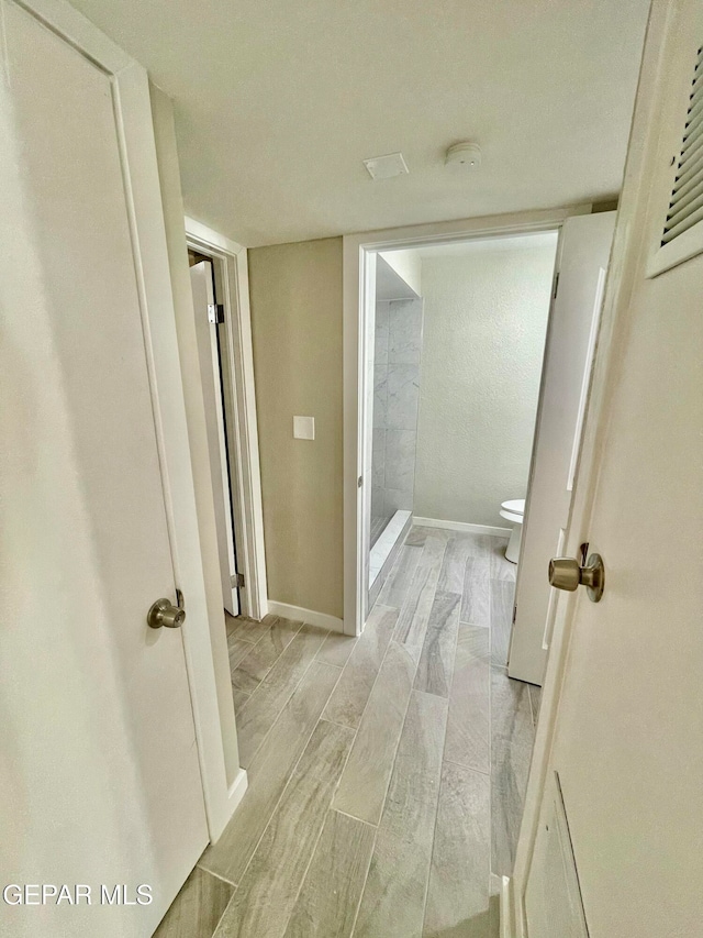 bathroom featuring toilet, wood-type flooring, and walk in shower