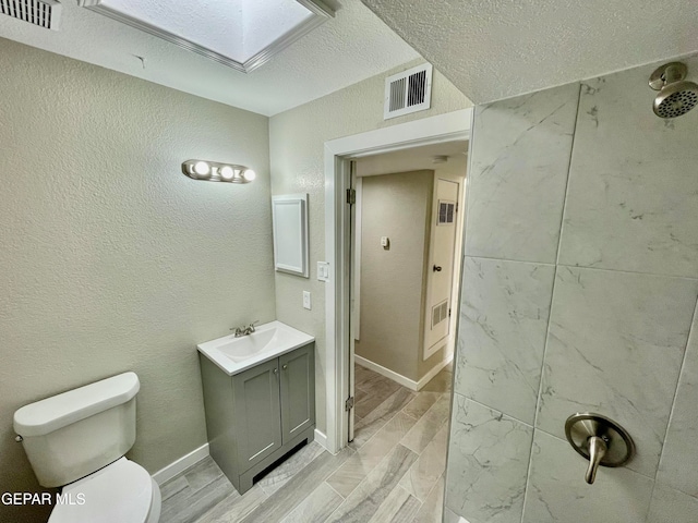 bathroom featuring a skylight, vanity, a textured ceiling, hardwood / wood-style floors, and toilet