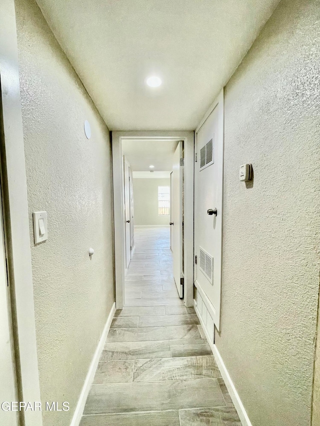 hallway featuring a textured ceiling and light hardwood / wood-style flooring