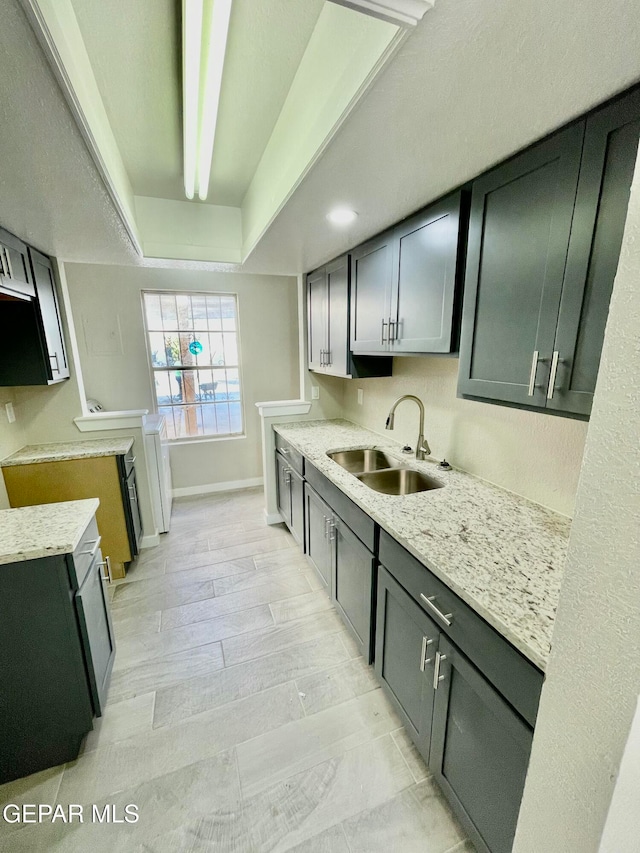 kitchen featuring light stone countertops, sink, and light hardwood / wood-style flooring