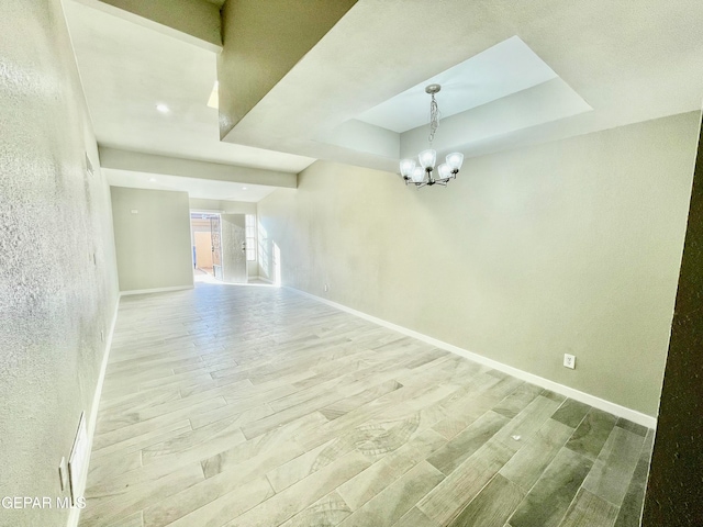 empty room with hardwood / wood-style floors and a notable chandelier