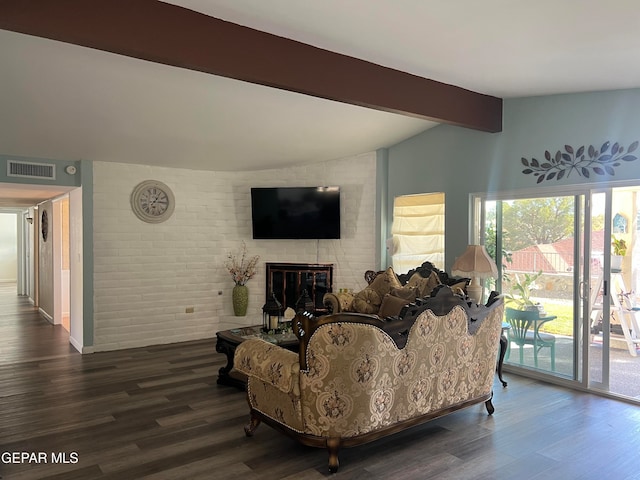 living room with dark hardwood / wood-style flooring, vaulted ceiling with beams, a fireplace, and brick wall