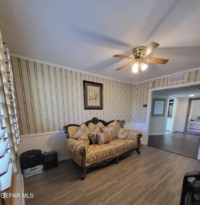 interior space with wood-type flooring, ornamental molding, and ceiling fan