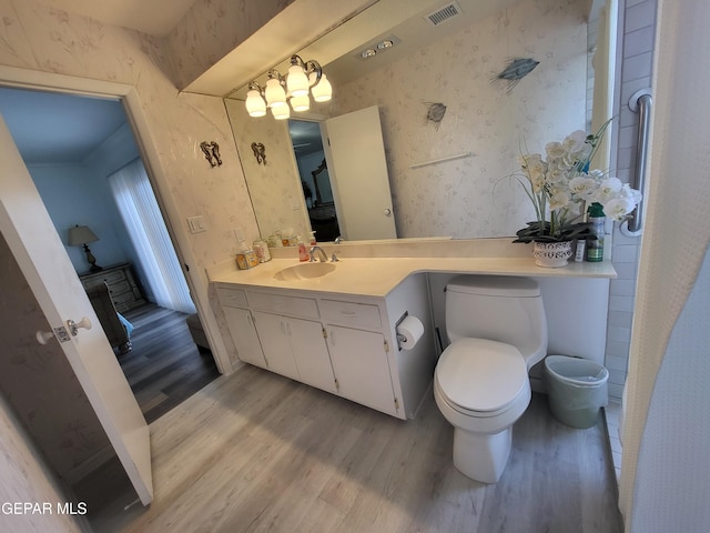 bathroom with a notable chandelier, wood-type flooring, vanity, and toilet