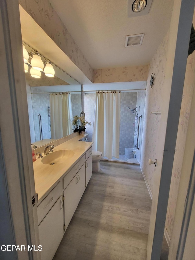 bathroom featuring hardwood / wood-style flooring, vanity, toilet, and walk in shower