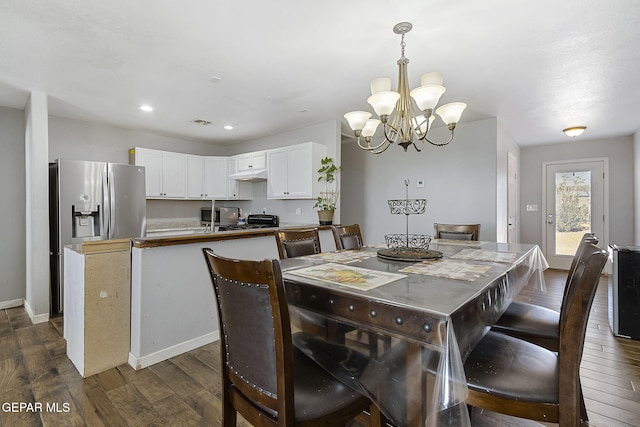 dining area featuring dark wood-type flooring and an inviting chandelier