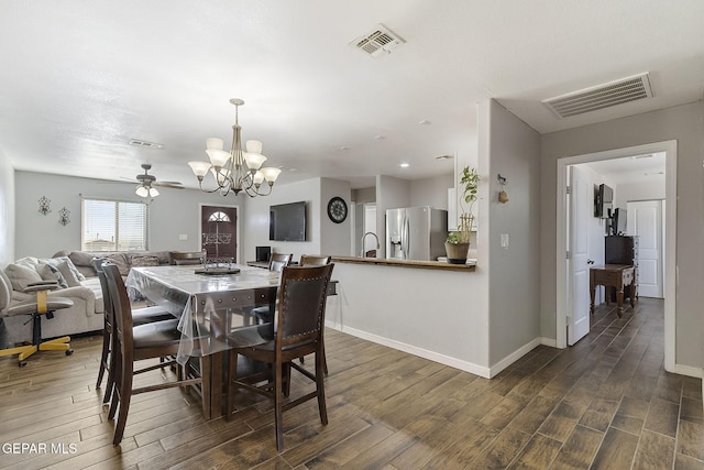 dining space featuring ceiling fan with notable chandelier and dark hardwood / wood-style floors