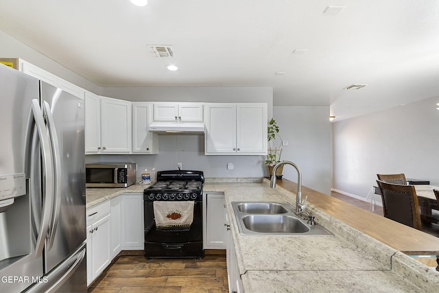 kitchen with sink, dark wood-type flooring, stainless steel appliances, range hood, and white cabinets