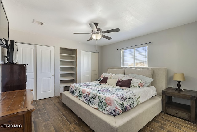 bedroom with multiple closets, ceiling fan, and dark hardwood / wood-style floors