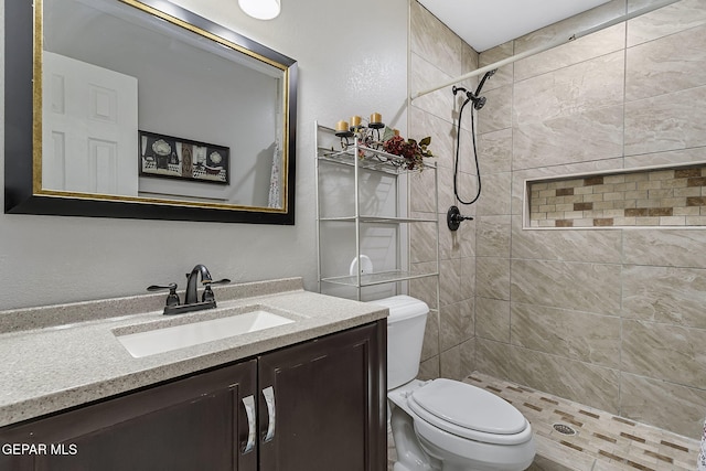 bathroom with tiled shower, vanity, and toilet