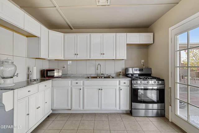 kitchen with stainless steel gas range oven, white cabinetry, sink, and light tile patterned floors