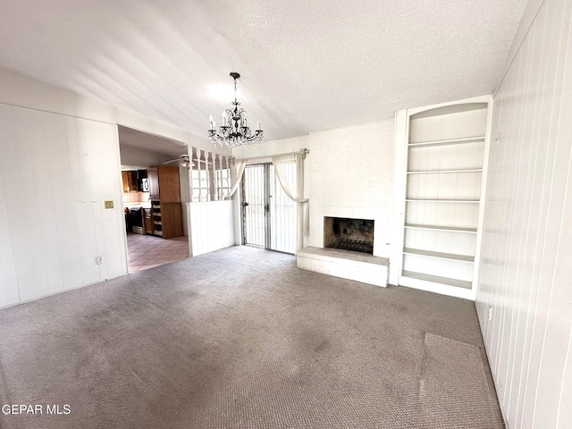 unfurnished living room featuring light carpet, a large fireplace, a textured ceiling, and a notable chandelier