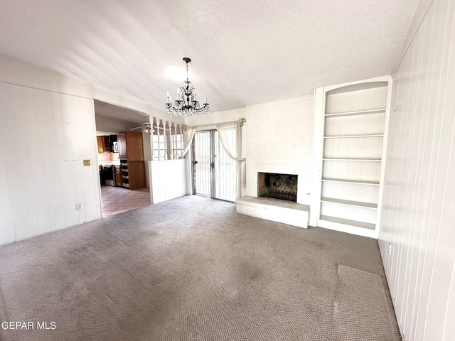 10545 Springwood Dr, El Paso, TX 79925 - unfurnished living room featuring a chandelier, carpet, a fireplace, built in shelves, and a textured ceiling