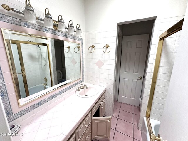 10545 Springwood Dr, El Paso, TX 79925 - full bathroom featuring tile patterned flooring, double vanity, shower / bath combination with glass door, tile walls, and toilet