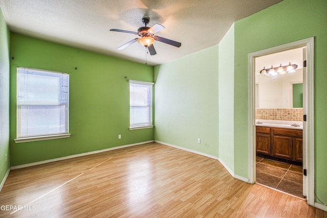 unfurnished bedroom with ceiling fan, connected bathroom, and light hardwood / wood-style flooring