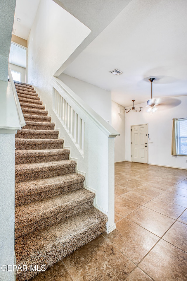 stairway featuring tile patterned floors, ceiling fan, and a healthy amount of sunlight