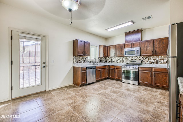 kitchen featuring decorative backsplash, ceiling fan, light tile patterned floors, and appliances with stainless steel finishes