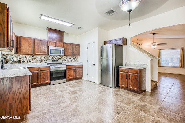 kitchen with tasteful backsplash, stainless steel appliances, ceiling fan, sink, and light tile patterned floors