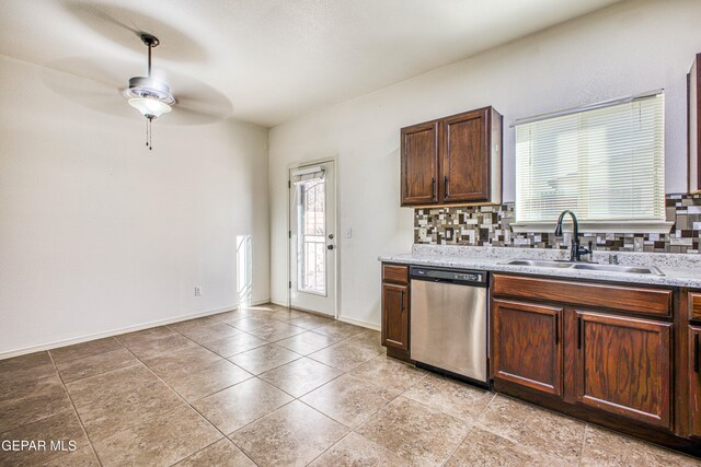 kitchen with stainless steel dishwasher, decorative backsplash, light stone counters, and sink