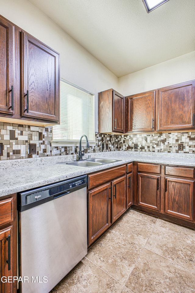 kitchen featuring dishwasher, light stone counters, sink, and tasteful backsplash