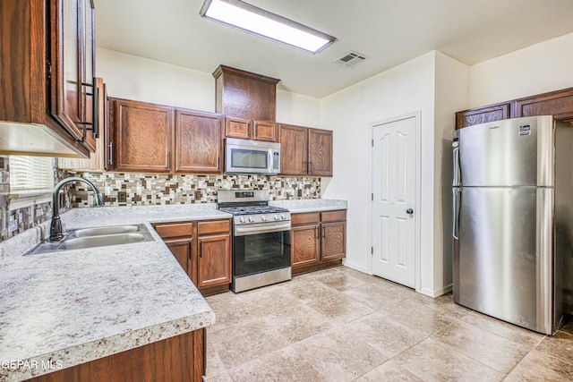 kitchen with backsplash, sink, light tile patterned floors, and stainless steel appliances