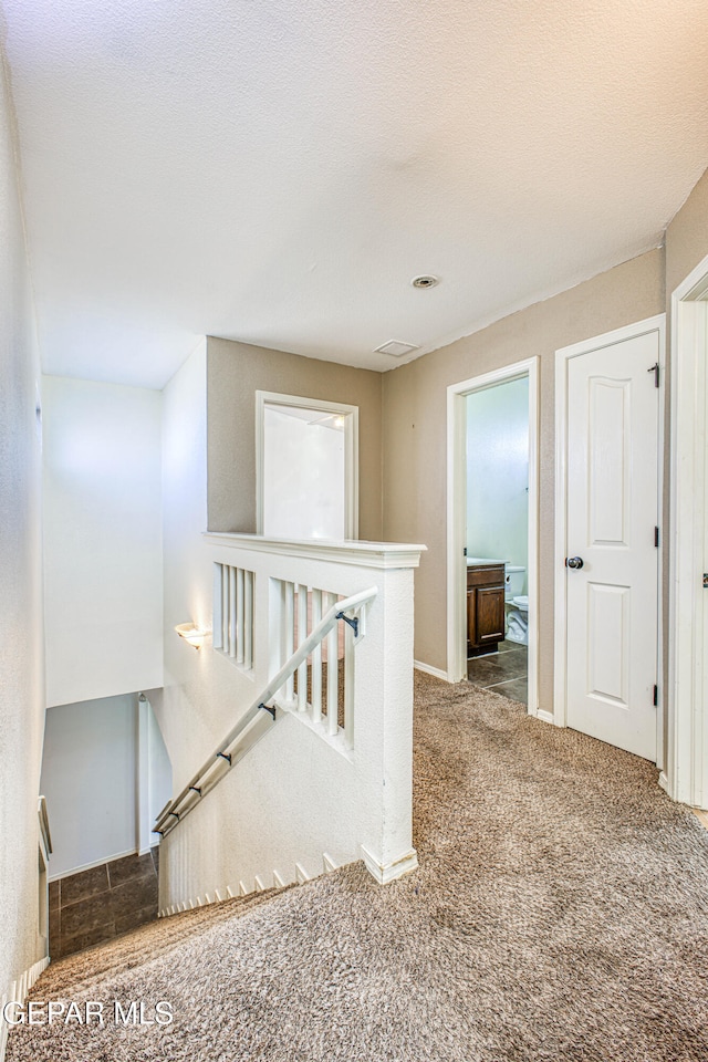 hall featuring carpet and a textured ceiling