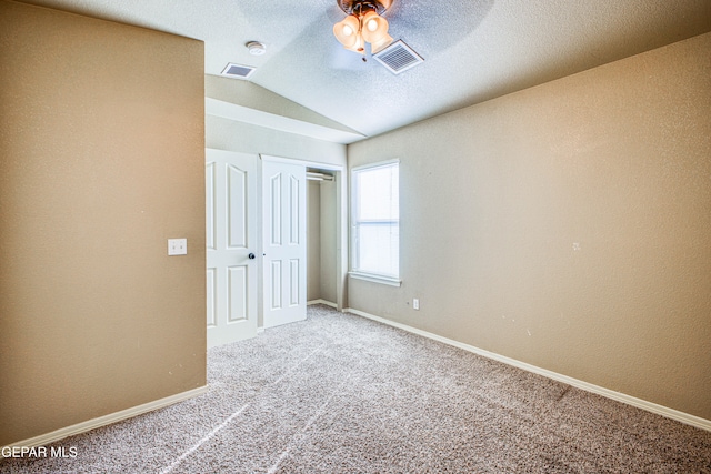 unfurnished bedroom with carpet flooring, ceiling fan, a textured ceiling, vaulted ceiling, and a closet