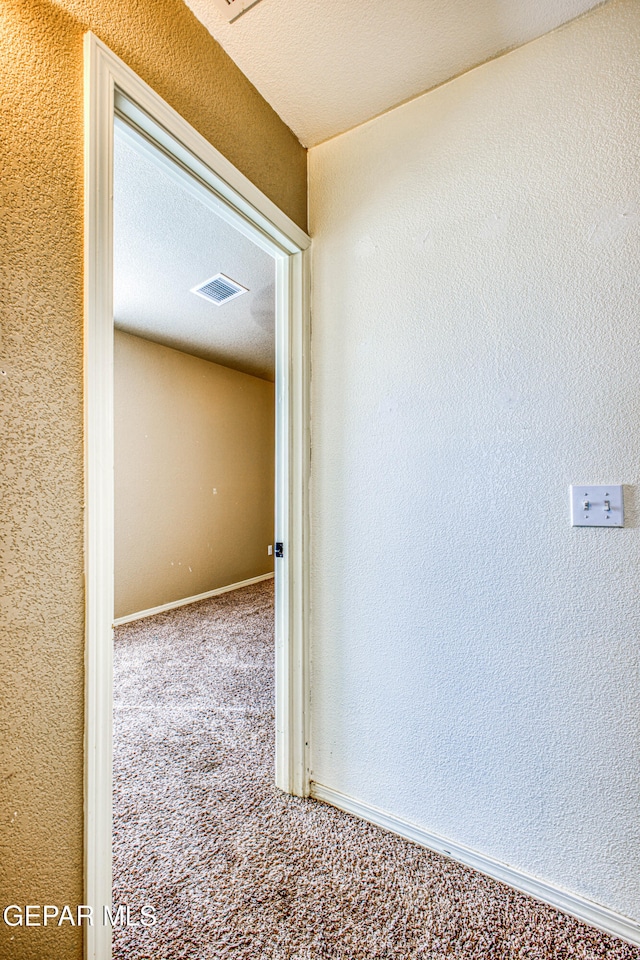 hall with carpet flooring and a textured ceiling