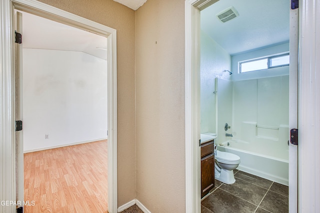 full bathroom featuring shower / bathing tub combination, vanity, lofted ceiling, hardwood / wood-style flooring, and toilet