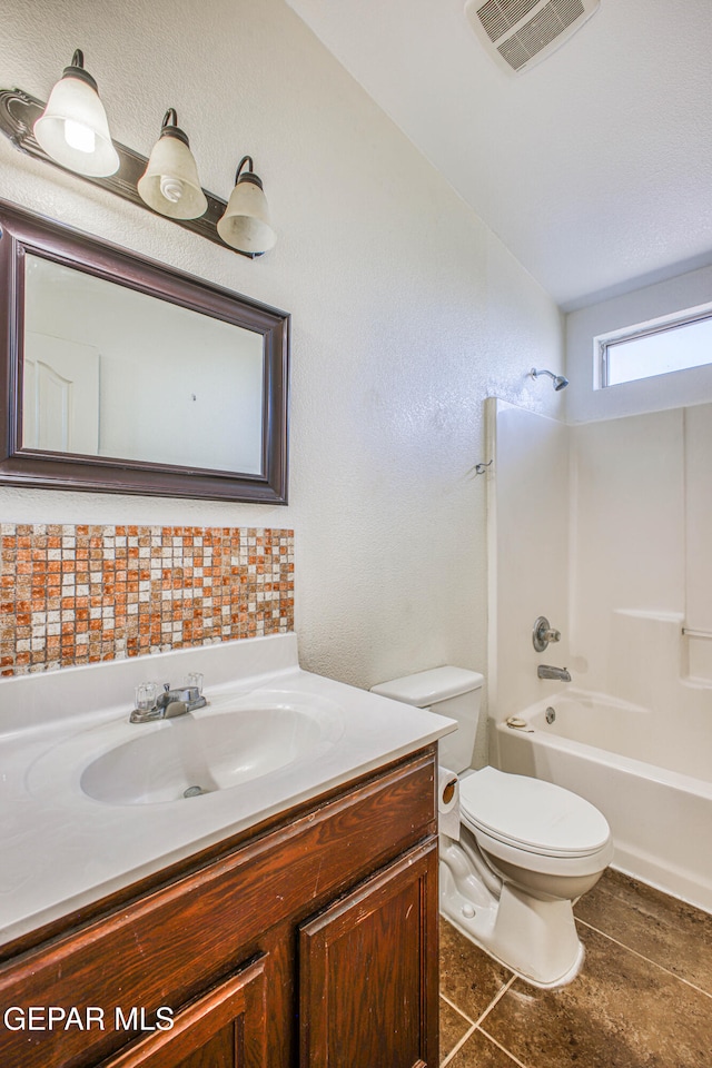 full bathroom featuring washtub / shower combination, tile patterned floors, lofted ceiling, toilet, and vanity