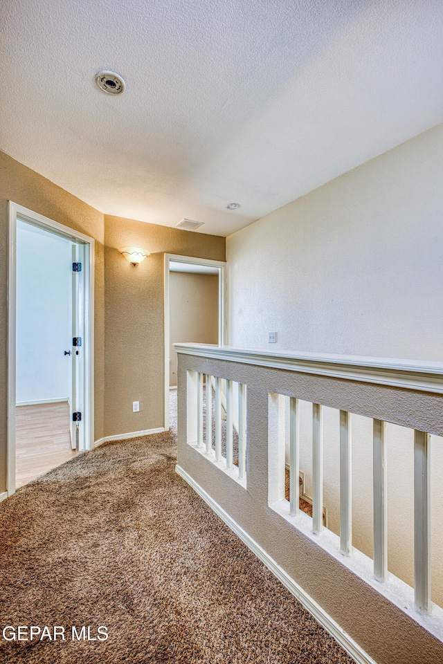 corridor with carpet flooring and a textured ceiling