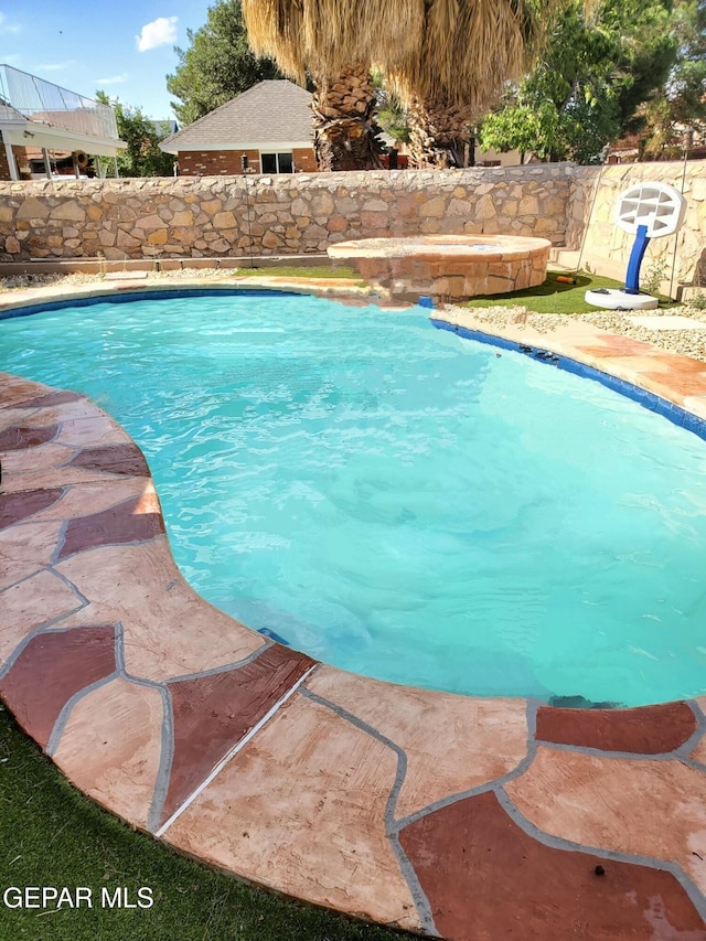 view of swimming pool with an in ground hot tub