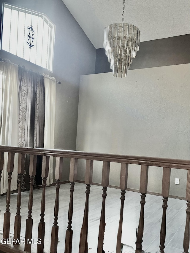 stairway featuring wood-type flooring, high vaulted ceiling, and a notable chandelier