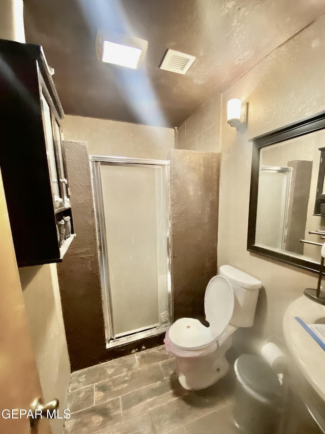 bathroom featuring a shower with shower door and toilet