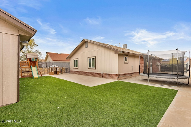 back of property with a playground, a yard, a patio, and a trampoline