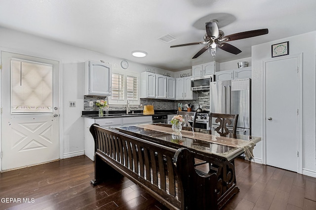 kitchen with white cabinets, dark hardwood / wood-style flooring, stainless steel appliances, and backsplash