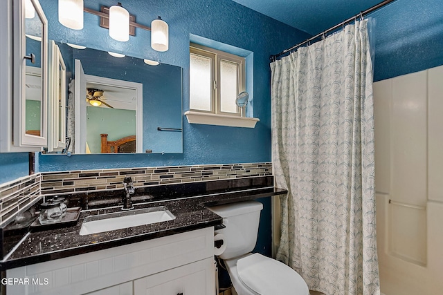 bathroom with a shower with shower curtain, tasteful backsplash, vanity, ceiling fan, and toilet